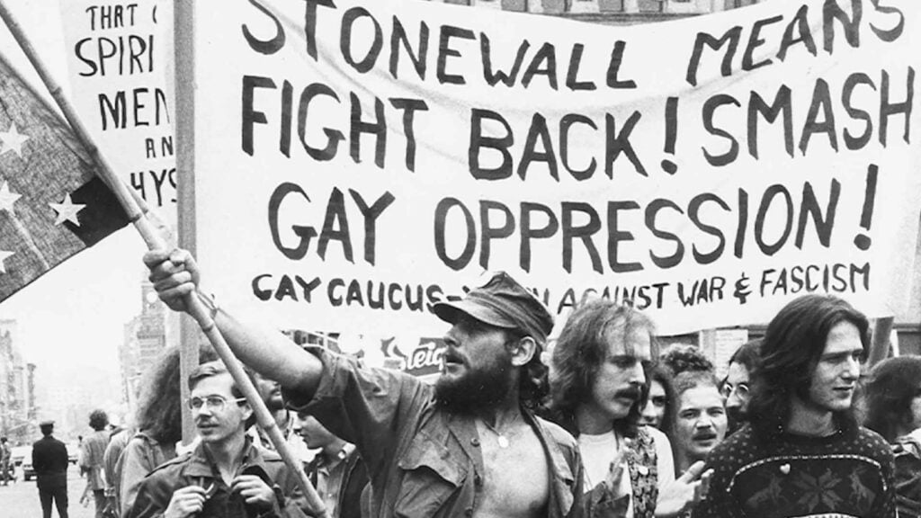 storia del gay pride moti di stonewall oppressione gay uomo con bandiera stonewall inn